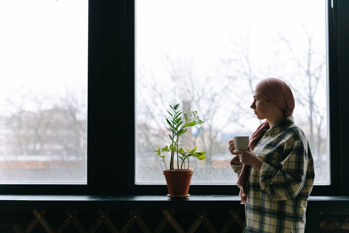 Woman holding a mug, looking calmly out of a window