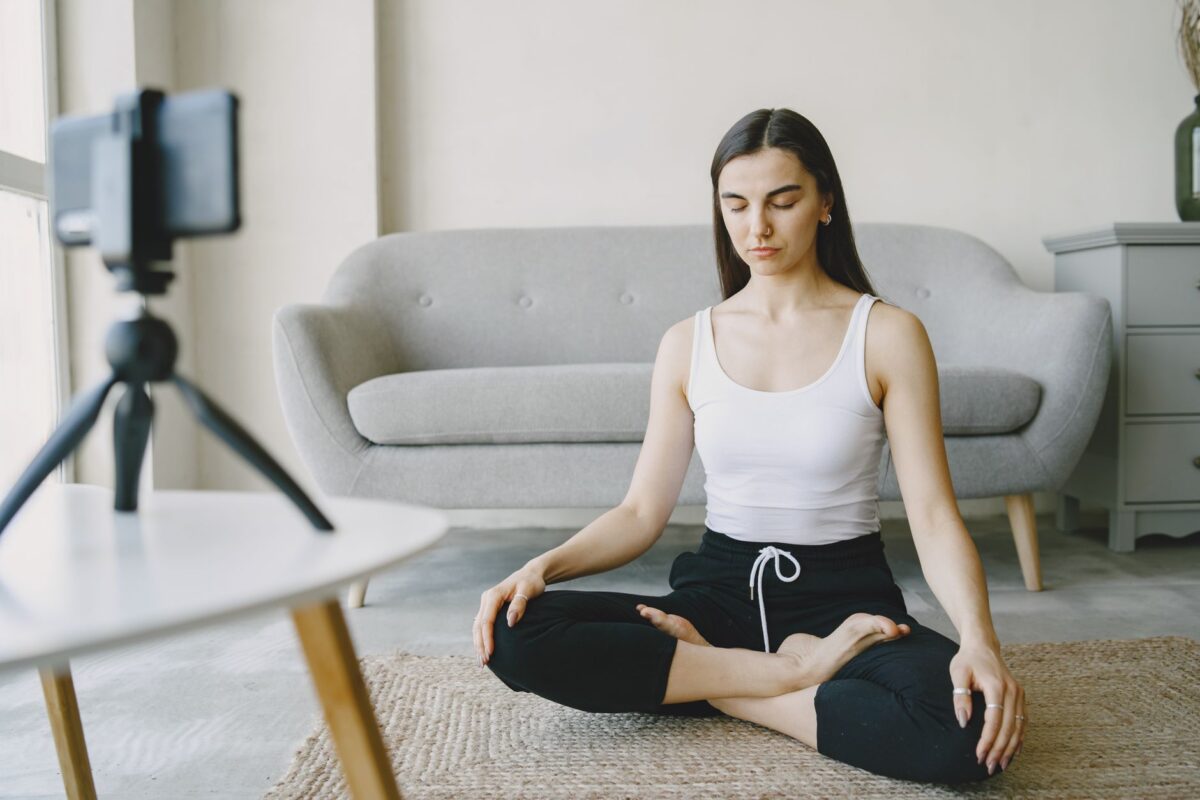Woman meditating cross-legged on the floor at home