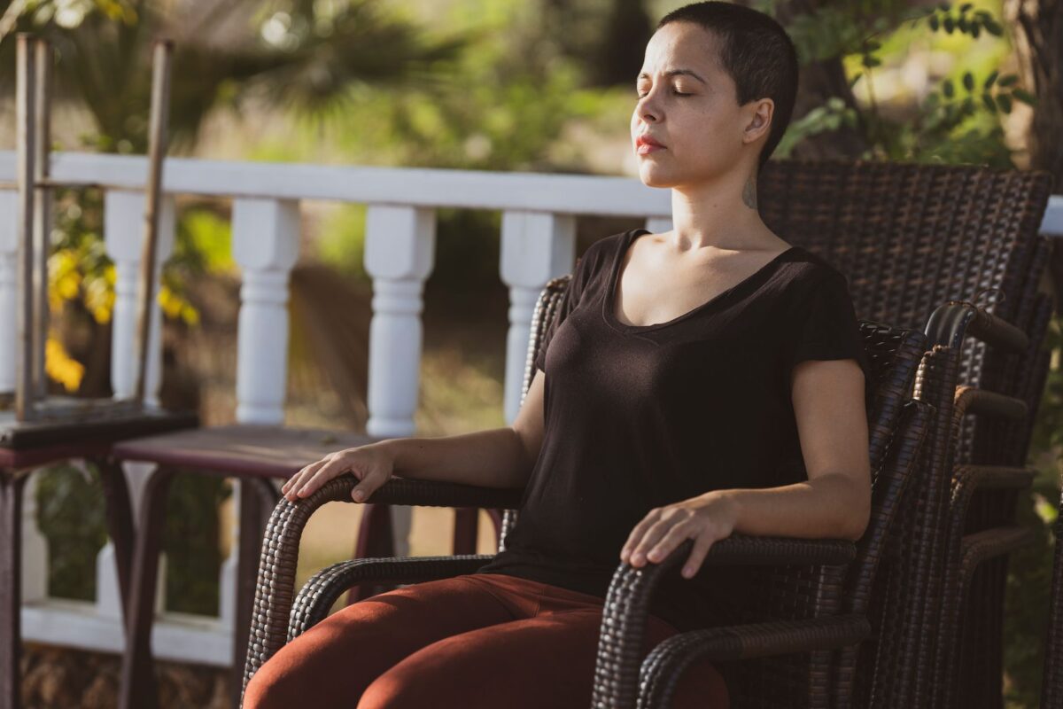 Woman sitting upright in a chair with her eyes closed and hands resting on the chair arms