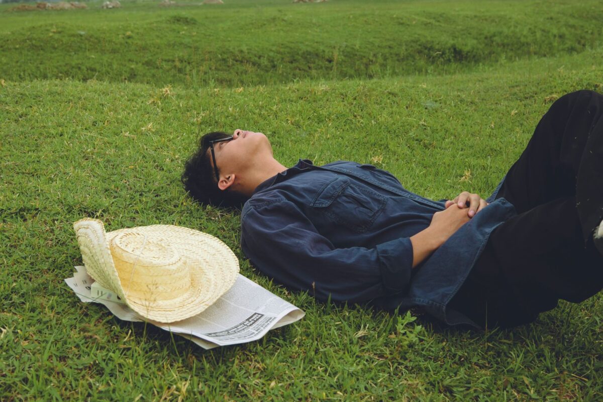 Man lying relaxed on grass with his hands resting on his stomach
