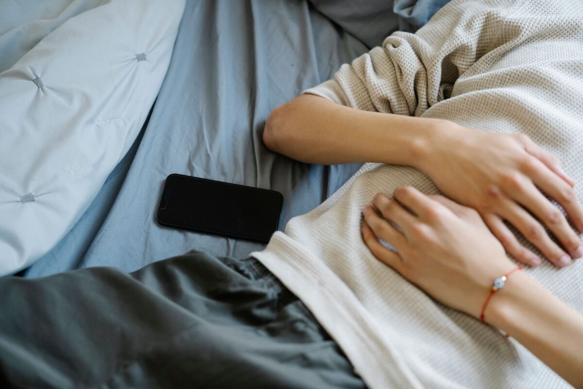 Person resting on a bed with their phone set aside