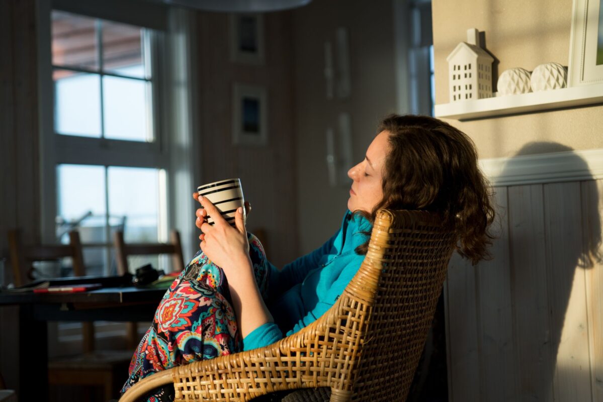 Woman relaxing in an armchair at home with a warm drink