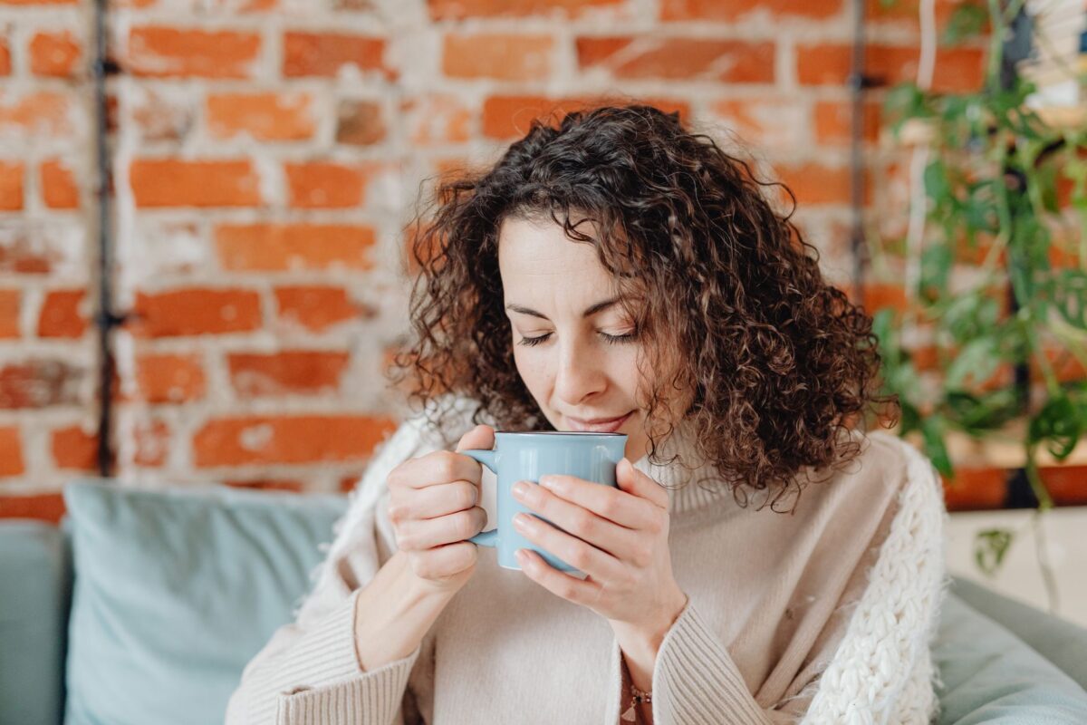 Woman with curly hair enjoying a warm cup of tea at home