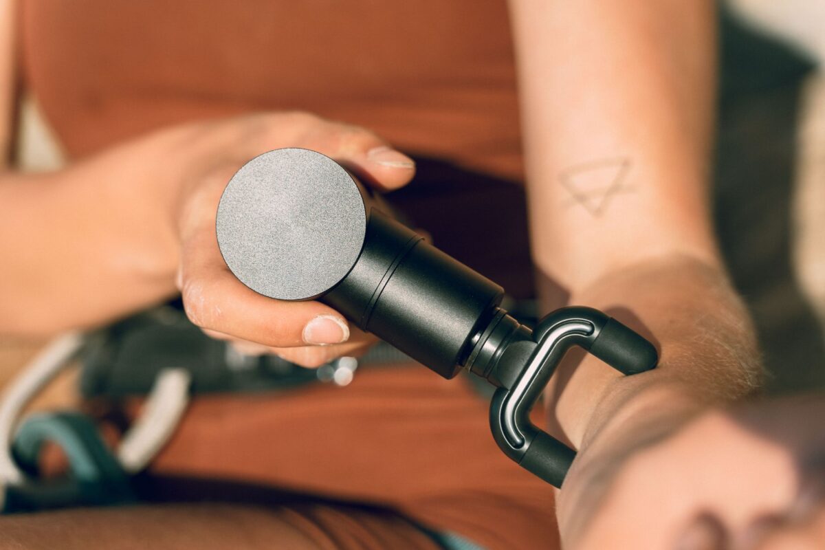Close-up of a hand holding a massage gun fitted with a fork-shaped head