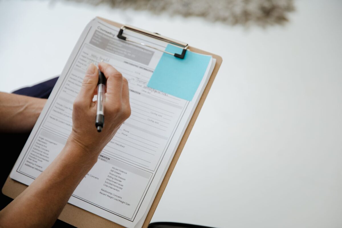 Person filling in a form on a clipboard