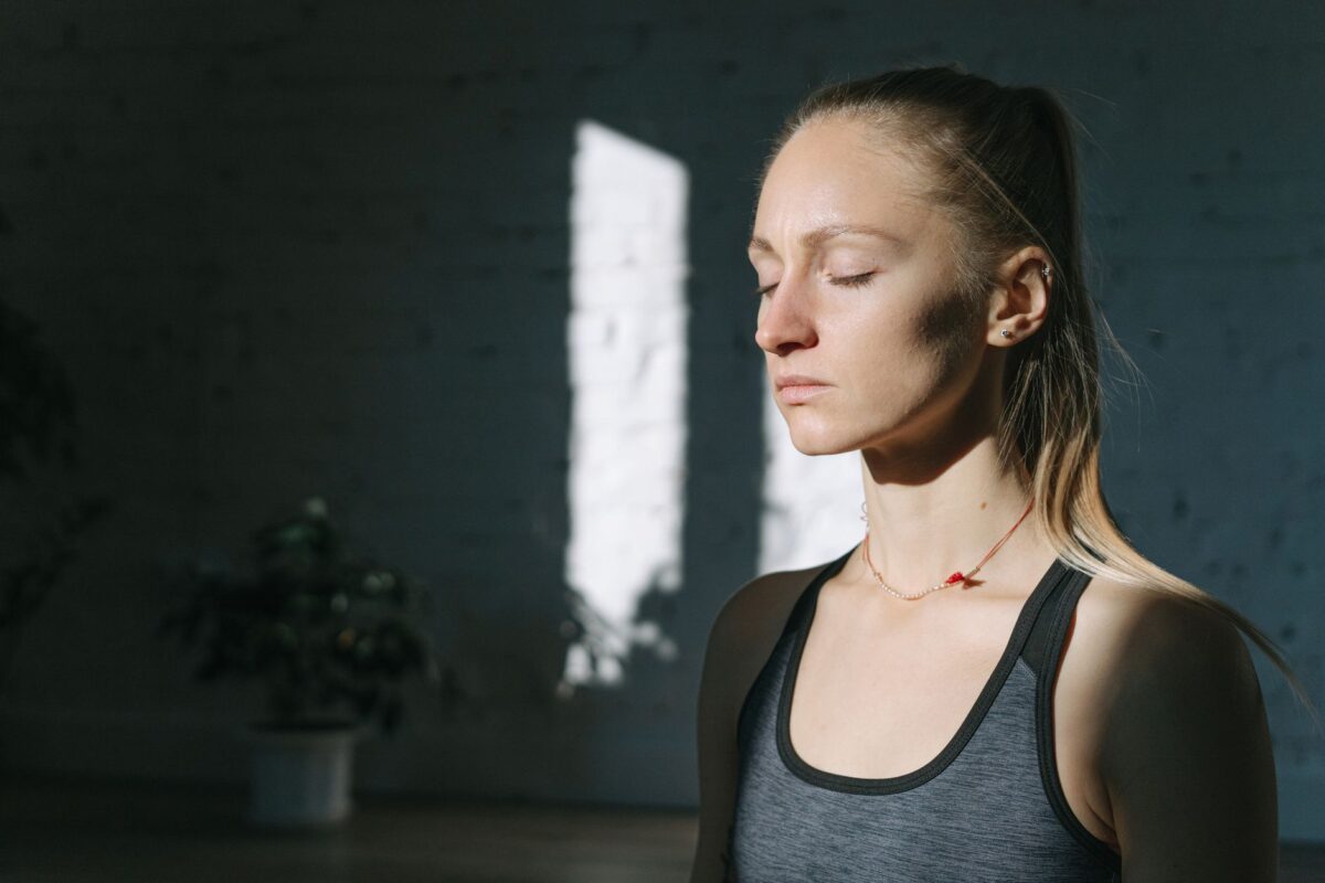 Woman sitting calmly with eyes closed in a sunlit room