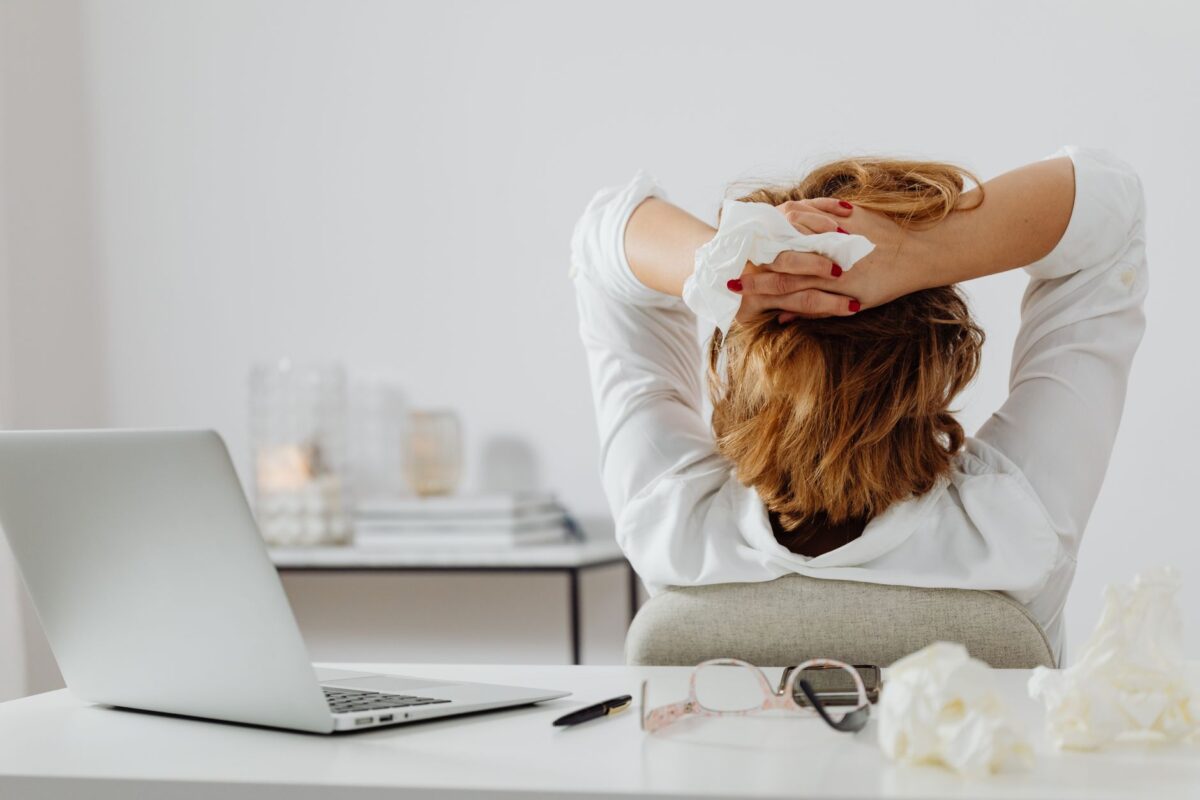 Woman leaning back from her laptop with hands behind her head, taking a short break