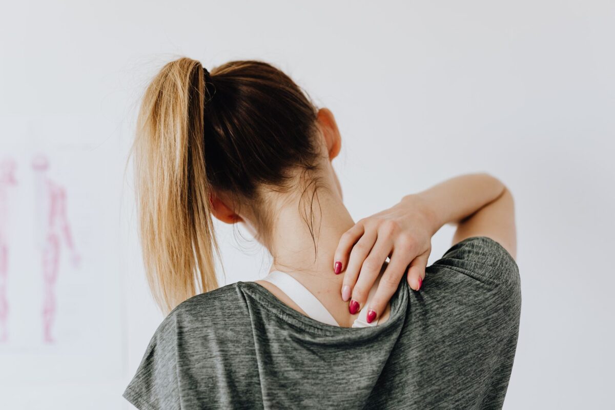Woman reaching across to massage the top of her own shoulder