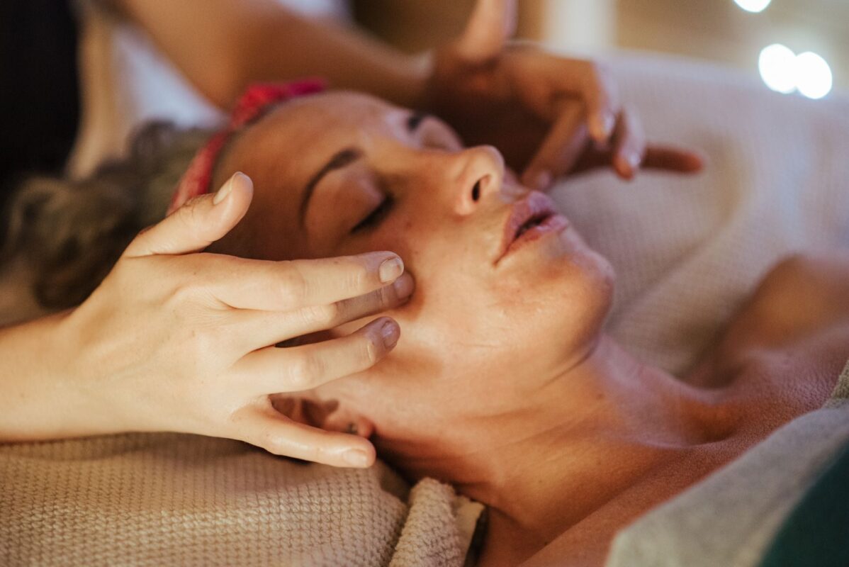 Therapist's fingertips massaging the temple of a relaxed client with closed eyes during a facial massage
